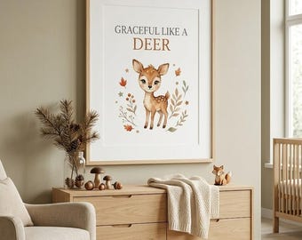 May include: A framed wall art print featuring a watercolor illustration of a fawn surrounded by autumn leaves and berries, with the text "GRACEFUL LIKE A DEER" printed in dark gray and brown lettering above the animal on a white background.