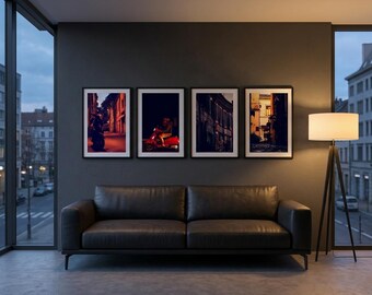 May include: A dark gray leather sofa positioned beneath four framed rectangular wall art prints. The prints feature urban street scenes with a red scooter and architectural details. A tripod floor lamp with a white drum shade stands nearby.