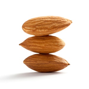 Puede incluir: Tres almendras apiladas una encima de la otra, con la almendra superior ligeramente inclinada hacia la derecha.