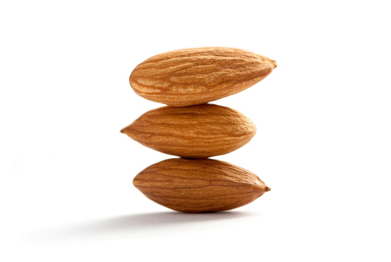 Puede incluir: Tres almendras apiladas una encima de la otra, con la almendra superior ligeramente inclinada hacia la derecha.