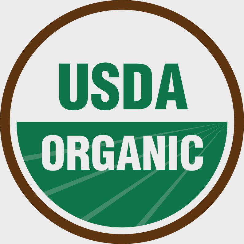 May include: A circular USDA Organic seal with a brown border. The top half of the circle is white with the text "USDA" in green. The bottom half is green with the word "ORGANIC" in white.