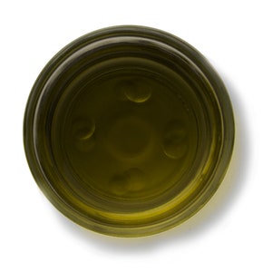 May include: A clear glass jar filled with a golden yellow liquid, possibly olive oil or honey. The jar has a wide mouth and a thick rim.