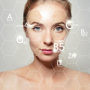 May include: A woman's face with a hexagonal grid overlay. The grid highlights different vitamins and minerals, including vitamin A, omega 6, Q10, vitamin C, vitamin B12, B5, zinc, and vitamin D.