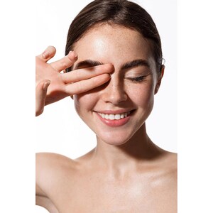 May include: A close-up portrait of a person with freckles smiling with their eyes closed. Their hand is covering one eye.