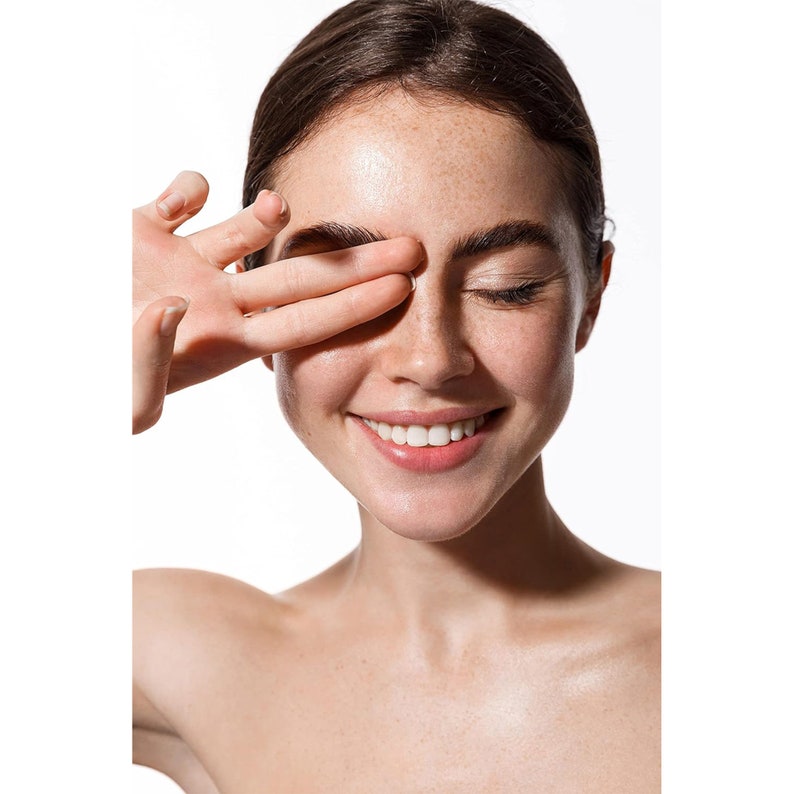 May include: A close-up portrait of a person with freckles smiling with their eyes closed. Their hand is covering one eye.