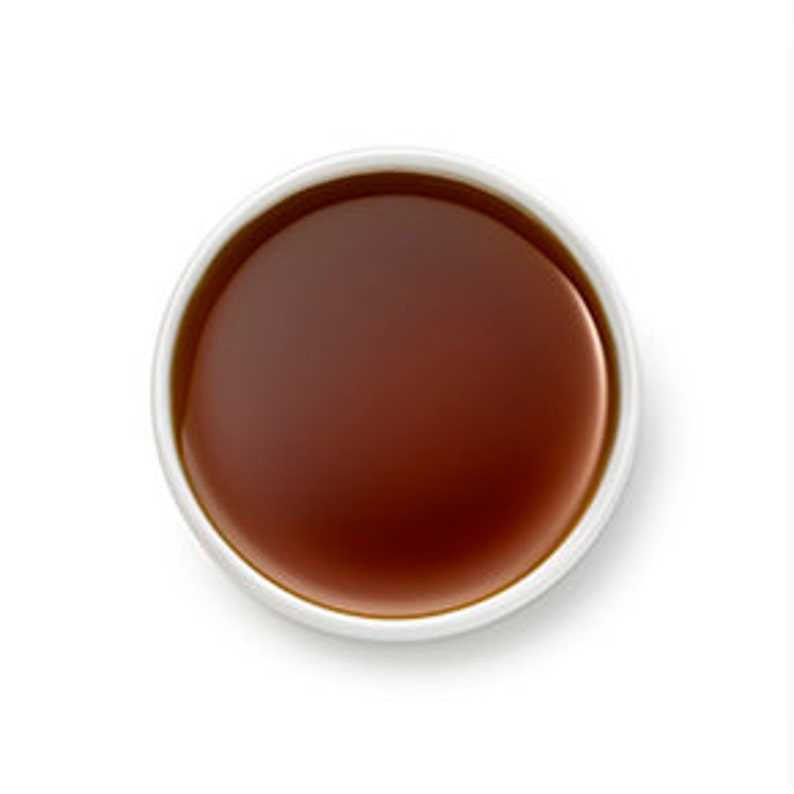 Op de afbeelding: Een kleine kom met donkerbruine vloeistof, mogelijk sojasaus.