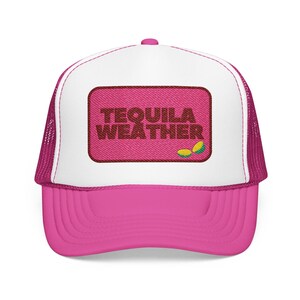May include: A bright pink and white trucker hat featuring a rectangular patch on the front. The patch is pink with dark brown embroidered text that reads TEQUILA WEATHER and includes a small green and yellow lime wedge graphic.