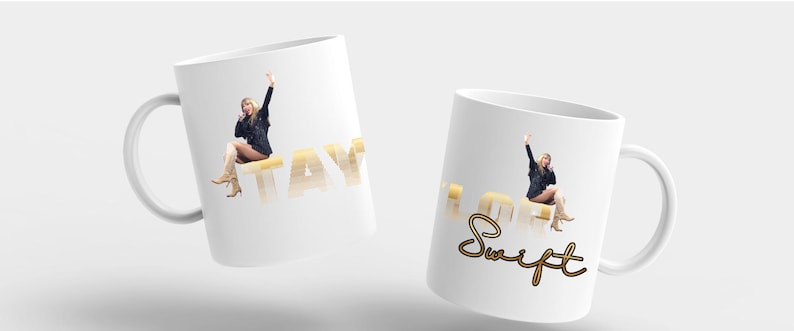 Puede incluir: Dos tazas de cer&aacute;mica blanca con asa. Una taza tiene la palabra "TAY" en letras doradas con la imagen de una persona. La otra taza tiene la palabra "Swift" en letras doradas con la imagen de una persona.
