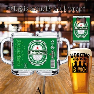 May include: A clear glass beer mug featuring a full-wrap green Heineken label with a red star, white text, and a barcode. Beside it, a tall glass filled with golden beer displays the black text 'WORKING on my 6 PACK' above a bottle icon.