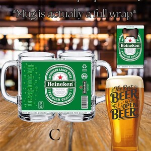 May include: A clear glass beer mug featuring a green Heineken label wrap with the text Heineken Lager Beer Premium Quality, a 20 fl. oz. capacity, and a barcode. Next to it is a tall glass filled with beer and the text The Best Beer is an Open Beer.