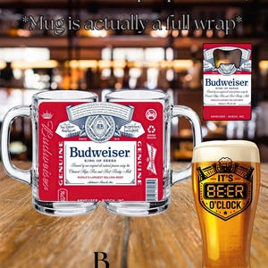 May include: A clear glass beer mug featuring a full-wrap Budweiser label with red, white, and blue branding, text, and a barcode. Beside it is a tall glass filled with beer, displaying the black text 'IT'S BEER O'CLOCK' and a graphic icon.