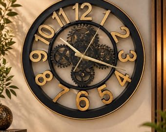 May include: A round wall clock featuring a black outer frame and large gold-colored numerals from one to twelve. The center displays exposed, dark-toned mechanical gears with gold-colored clock hands, creating a visible industrial-style movement.