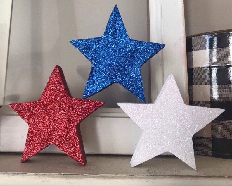 May include: Three glitter foam stars in red, white, and blue. The stars are a popular decoration for patriotic holidays.