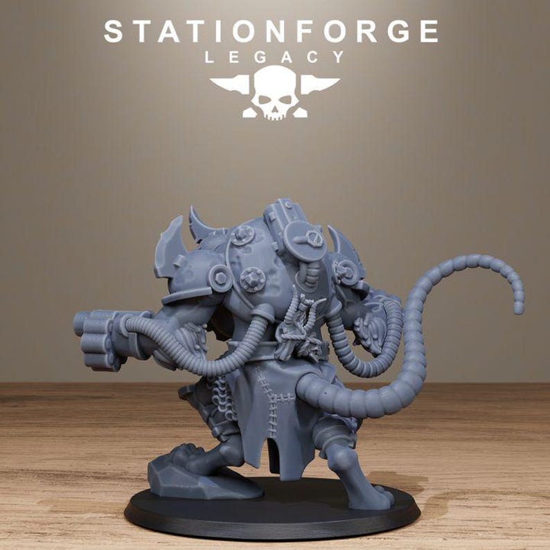 May include: A grey resin miniature figure of a creature with a long segmented tail, wearing armoured plating with circular details, connected by tubes to a weapon on its arm, standing on a circular base with the text STATIONFORGE LEGACY above.