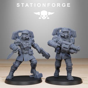 May include: Two grey unpainted miniature soldier figurines from StationForge. Each figure wears tactical armour, a helmet with a respirator, and a backpack. One figure holds a knife and a pistol, while the other carries a large heavy weapon.