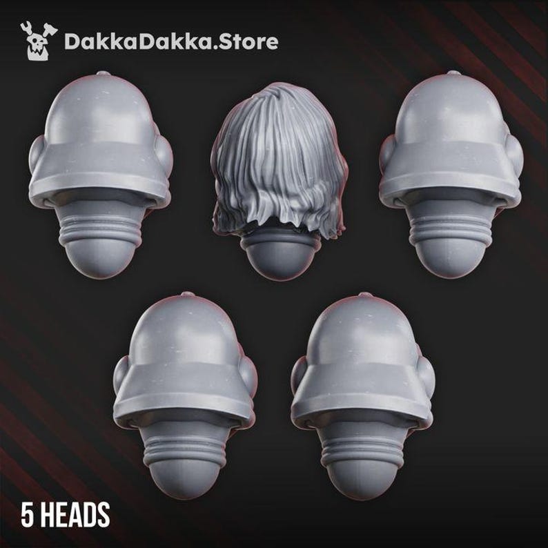 Puede incluir: Cinco cabezas en miniatura grises para figuras de juego, incluyendo cuatro cascos lisos id&eacute;nticos con parte superior redondeada y una cabeza con cabello ondulado texturizado. Cada pieza tiene una articulaci&oacute;n circular. Texto DakkaDakka.Store y 5 HEADS.