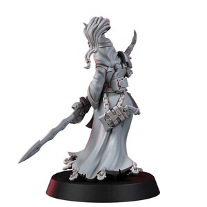 May include: A gray unpainted miniature figure of a character wearing a long flowing robe with a high collar and long hair. The figure holds a long sword in one hand and has a small pistol holstered at the hip, with a skull emblem on the back belt.