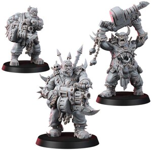 May include: Three unpainted gray miniature figures of muscular humanoid creatures with tusks and horns. Two figures hold large mechanical heavy weapons, while the third figure raises a massive bladed hammer overhead, adorned with hanging skull charms.