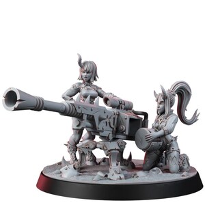 May include: A grey miniature figurine set featuring two horned figures operating a large, heavy-duty mounted cannon. One figure stands behind the weapon while the other kneels to load a circular ammunition drum. The piece is set on a round base.