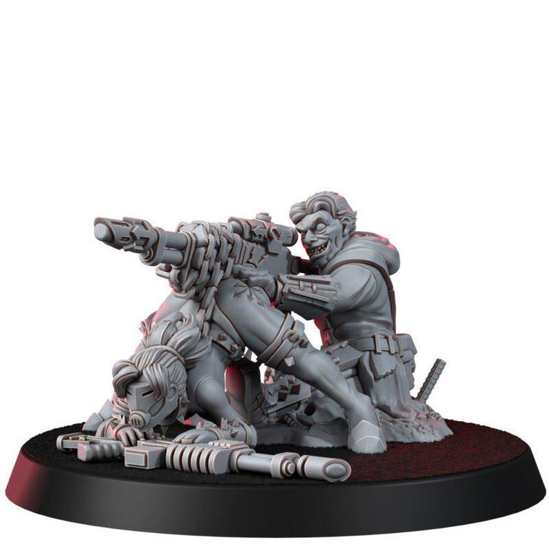 May include: A gray miniature figurine set featuring a crouching figure with a mask and a rifle, positioned in front of a second figure with a wide grin who is aiming a large, mounted heavy weapon. The figures are mounted on a circular base.