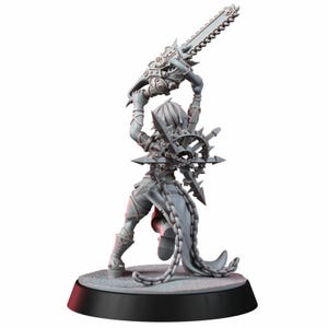 Op de afbeelding: Een grijze onbeschilderde miniatuurfiguur op een ronde voet, die een groot kettingzaagwapen boven het hoofd houdt. De figuur draagt een harnas met stekels, een stervormig embleem op de rug en lange kettingen rond de taille en benen.