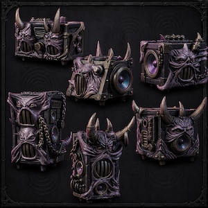 Puede incluir: Una colecci&oacute;n de cinco altavoces de color morado oscuro y negro con rostros demon&iacute;acos esculpidos, cuernos prominentes, cadenas met&aacute;licas integradas y conos de altavoz circulares. Cada unidad presenta un acabado texturizado y desgastado.