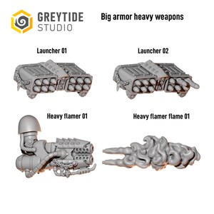 Op de afbeelding: Grijze plastic miniatuur spelonderdelen met het label Big armor heavy weapons, inclusief twee raketwerpers, een zware vlammenwerper met schouderstuk en een apart gevormd vlameffectstuk. De set bevat gedetailleerde mechanische onderdelen.