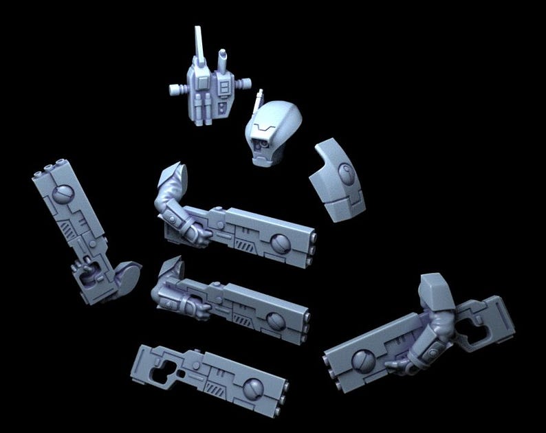 Op de afbeelding: Een lichtblauwe, onbeschilderde plastic modelbouwset met een robotachtig hoofd, een romp, een rugzak en diverse armonderdelen die lange, rechthoekige futuristische geweren vasthouden met cirkelvormige details en geometrische panelen.