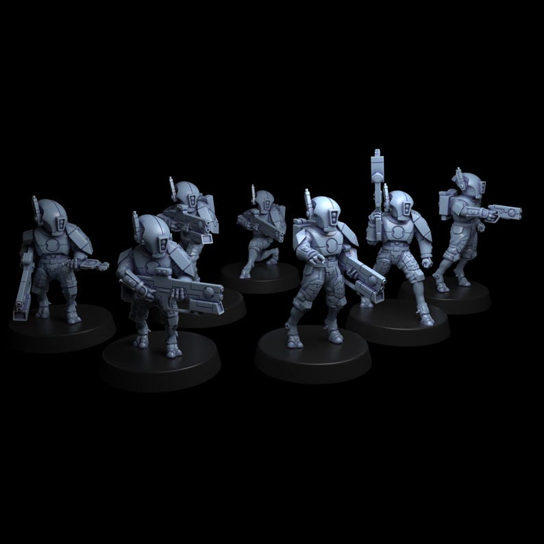 Op de afbeelding: Een set van zeven ongeverfde grijze miniatuurfiguren die futuristische soldaten voorstellen. Elke figuur draagt een gladde, afgeronde helm met een centraal vizier, gepantserde borstplaten en tactische uitrusting op ronde zwarte voetstukken.
