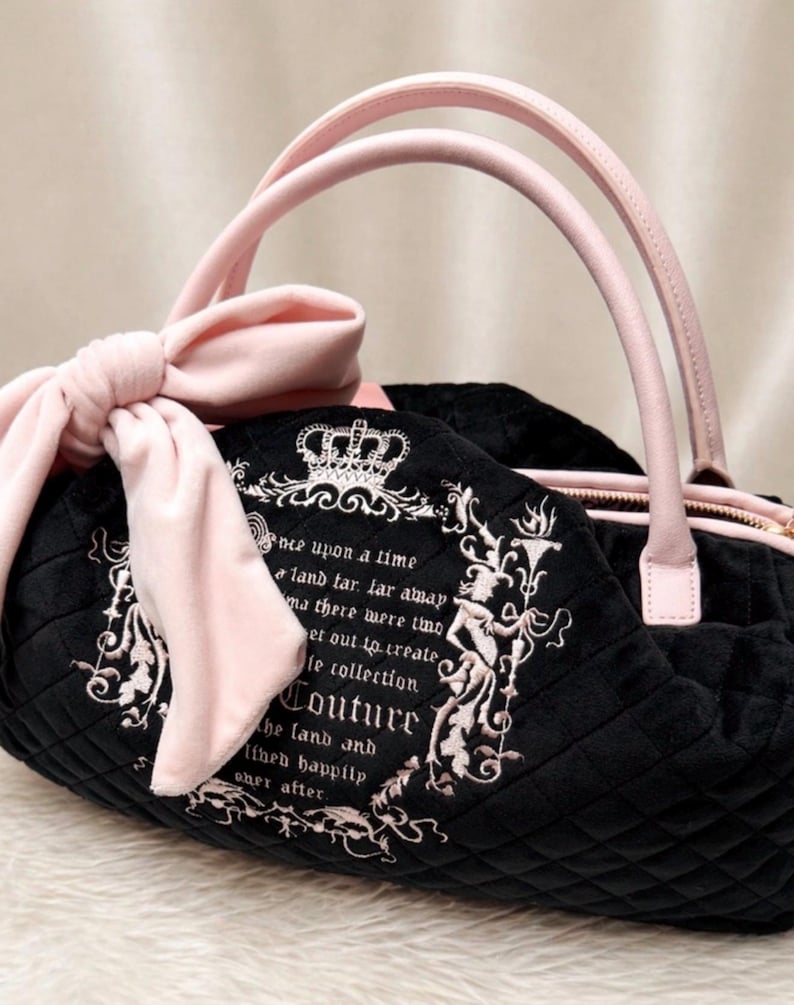 May include: A black quilted handbag featuring light pink handles and a large matching bow on the side. The front displays an embroidered crown and text that reads: Once upon a time a land far far away there were two set out to create the collection Couture the land and lived happily ever after.