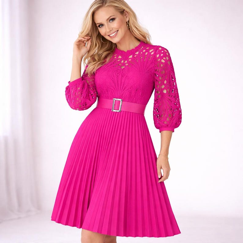 May include: A bright pink dress with a pleated skirt and a fitted bodice. The dress features a belt with a silver buckle and lace detailing on the sleeves and neckline. The dress has a knee-length hemline.