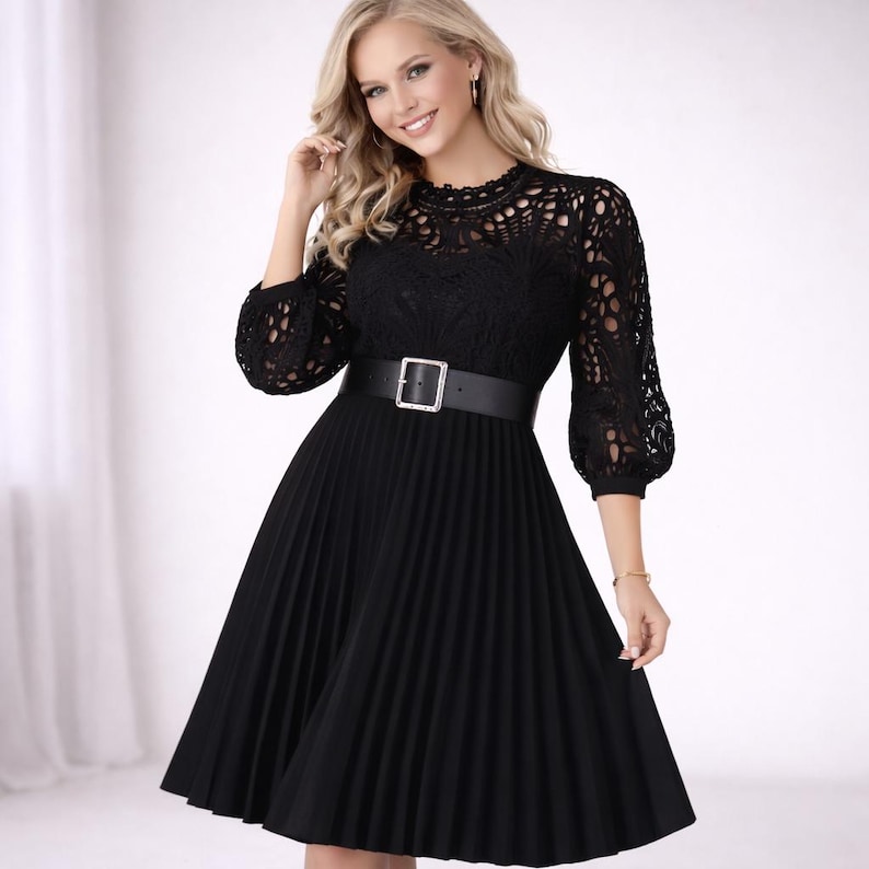 May include: Black dress featuring a lace bodice and pleated skirt. The dress has a high neckline, three-quarter sleeves, and a black belt with a silver buckle. The dress is knee-length and suitable for formal occasions.