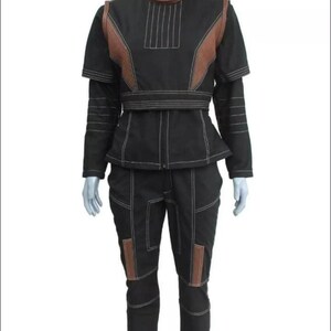 May include: A black two-piece outfit consisting of a short-sleeved top and matching pants. The top features a high collar, brown shoulder panels, and white topstitching. The pants have brown knee panels and white topstitching throughout the set.