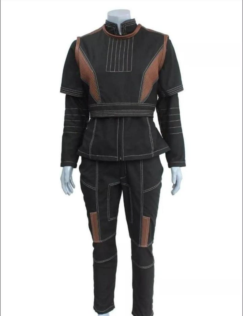 May include: A black two-piece outfit consisting of a short-sleeved top and matching pants. The top features a high collar, brown shoulder panels, and white topstitching. The pants have brown knee panels and white topstitching throughout the set.