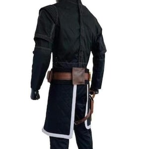 May include: Black costume with a jacket, pants, and a belt with pouches. The jacket has long sleeves and white stitching. The pants have a white trim. The belt is brown with a brown pouch.