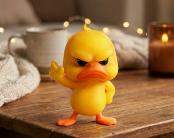 May include: A yellow duck figurine with an angry expression, orange beak and feet, and a raised wing. The duck is standing on a wooden surface. The figurine has a cartoonish design.