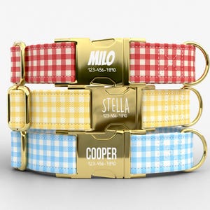 May include: Three pet collars featuring a gingham pattern in red, yellow, and light blue. Each collar has a gold-tone metal side-release buckle engraved with a name and phone number: MILO 123-456-7890, STELLA 123-456-7890, and COOPER 123-456-7890.