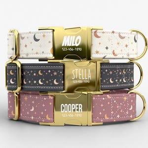 May include: Three personalized dog collars with gold-colored buckles. The collars feature celestial patterns of moons and stars in cream, dark gray, and mauve. Each buckle displays a name and phone number: MILO, STELLA, and COOPER.