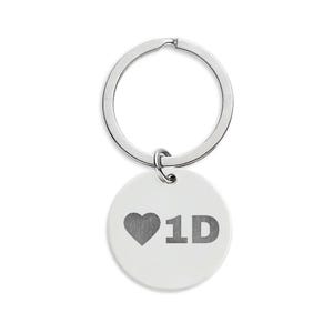 May include: A silver keyring with a round, white pendant. The pendant features a grey heart symbol followed by the letters "1D" in grey. The keyring ring is also silver.