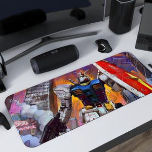 Può includere: Tappetino per mouse rettangolare con un'illustrazione colorata di un robot Gundam in un paesaggio urbano. Il robot è principalmente blu, bianco e rosso, con uno scudo. Lo sfondo include edifici e testo giapponese. Altri oggetti sulla scrivania bianca sono presenti.