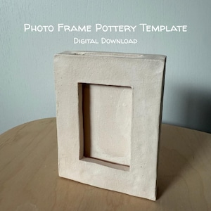 May include: A rectangular off-white ceramic photo frame with a smooth, matte finish and a central vertical opening. The text "PHOTO FRAME POTTERY TEMPLATE DIGITAL DOWNLOAD" is printed in white at the top of the image against a light blue background.