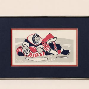 May include: Framed print featuring a stylized depiction of two figures in winter attire. The artwork uses red, white, and black colors, with a focus on the figures' clothing and activities. The print is set within a silver frame with a navy blue mat.
