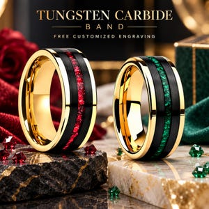 Puede incluir: Dos anillos de carburo de tungsteno con interior dorado y exterior negro cepillado con incrustaciones centrales. Un anillo tiene una incrustación de piedra roja triturada y el otro de piedra verde. Texto: TUNGSTEN CARBIDE BAND.