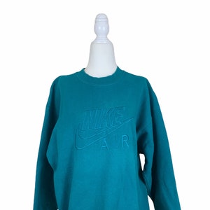 May include: Teal blue sweatshirt with a white embroidered Nike Air logo.