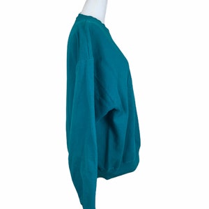 May include: Teal blue sweatshirt with a crew neck and long sleeves.