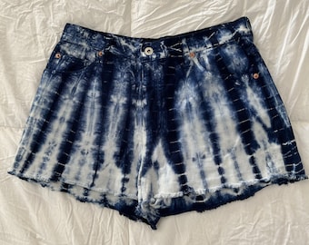 May include: Blue and white tie-dye denim shorts with a frayed hem.