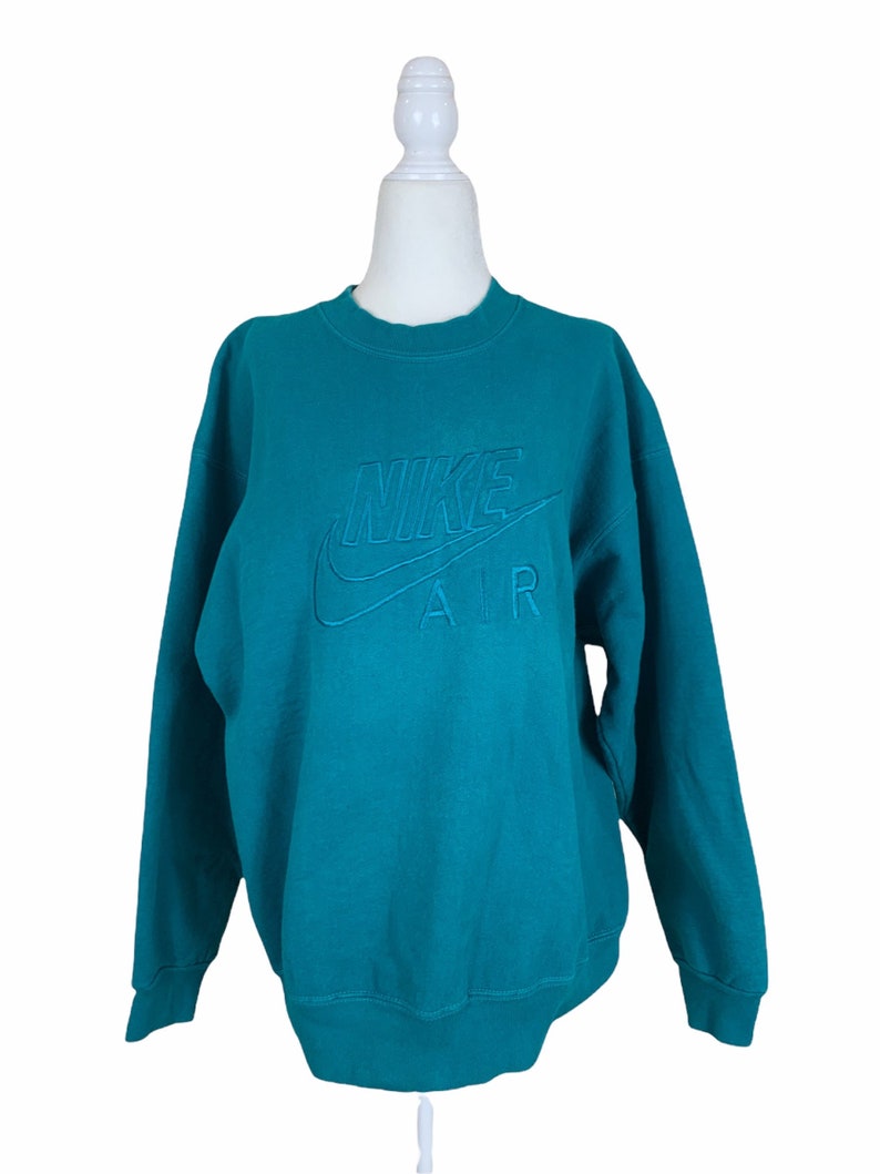 May include: Teal blue sweatshirt with a white embroidered Nike Air logo.