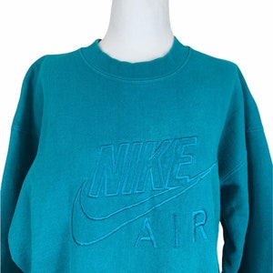 May include: Teal blue sweatshirt with a white embroidered Nike Air logo.