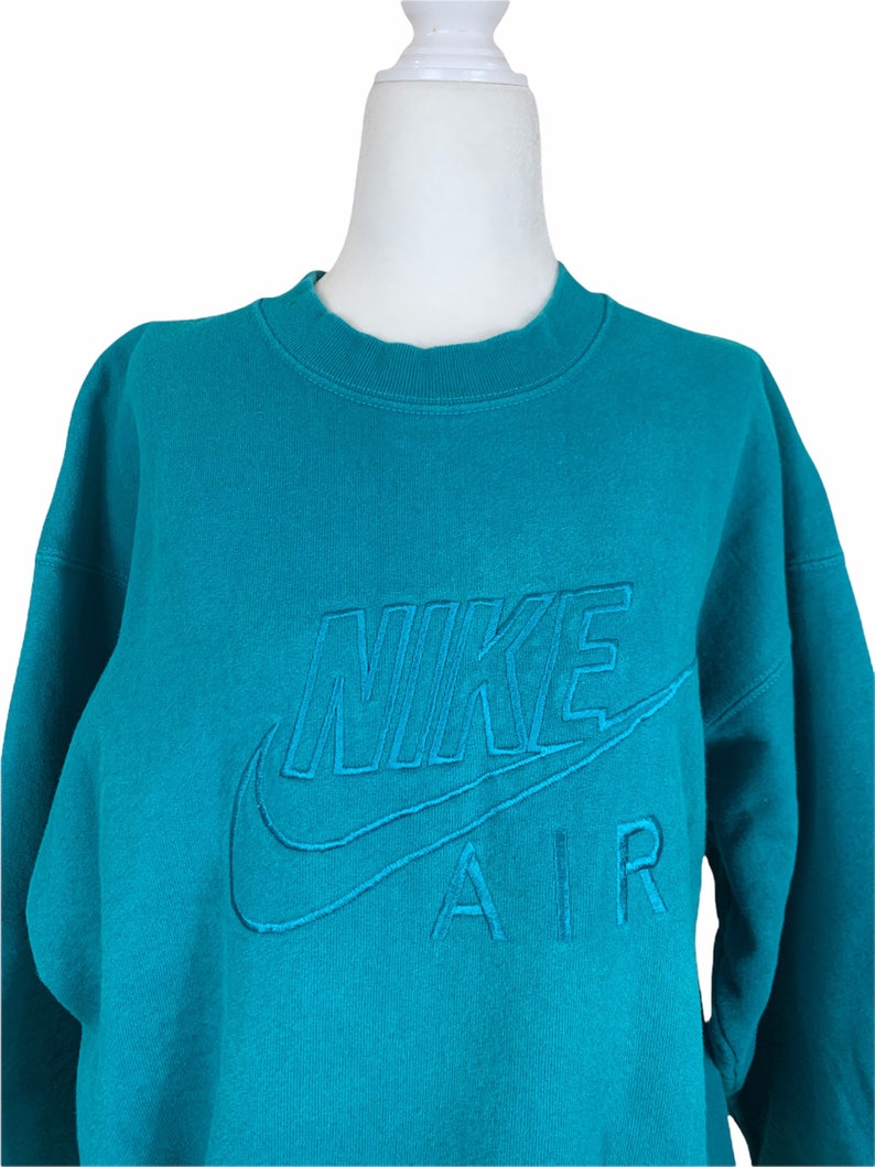 May include: Teal blue sweatshirt with a white embroidered Nike Air logo.