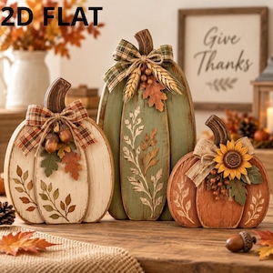 May include: Three decorative wooden pumpkin cutouts labeled 2D FLAT. The white pumpkin features a plaid bow and acorns, the green pumpkin has a plaid bow and wheat, and the orange pumpkin displays a sunflower and burlap bow.